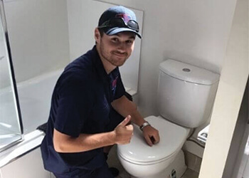 local plumber fixing broken bathroom toilet inside commercial shopping centre
